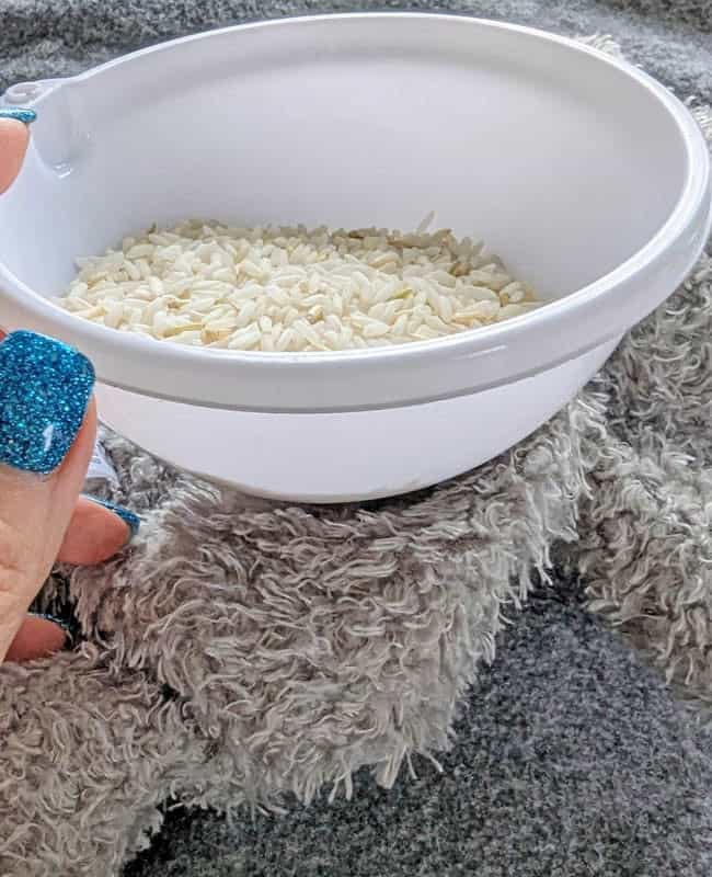 Close-up of a white bowl filled with rice placed on a fluffy plush surface for toy stuffing.