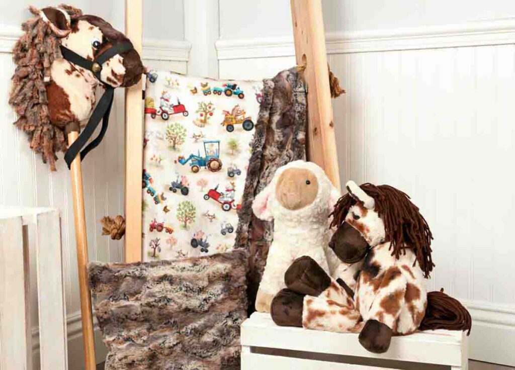 Plush horse and sheep toys displayed with faux fur fabrics and a hobby horse, showcasing realistic textures for toy making.