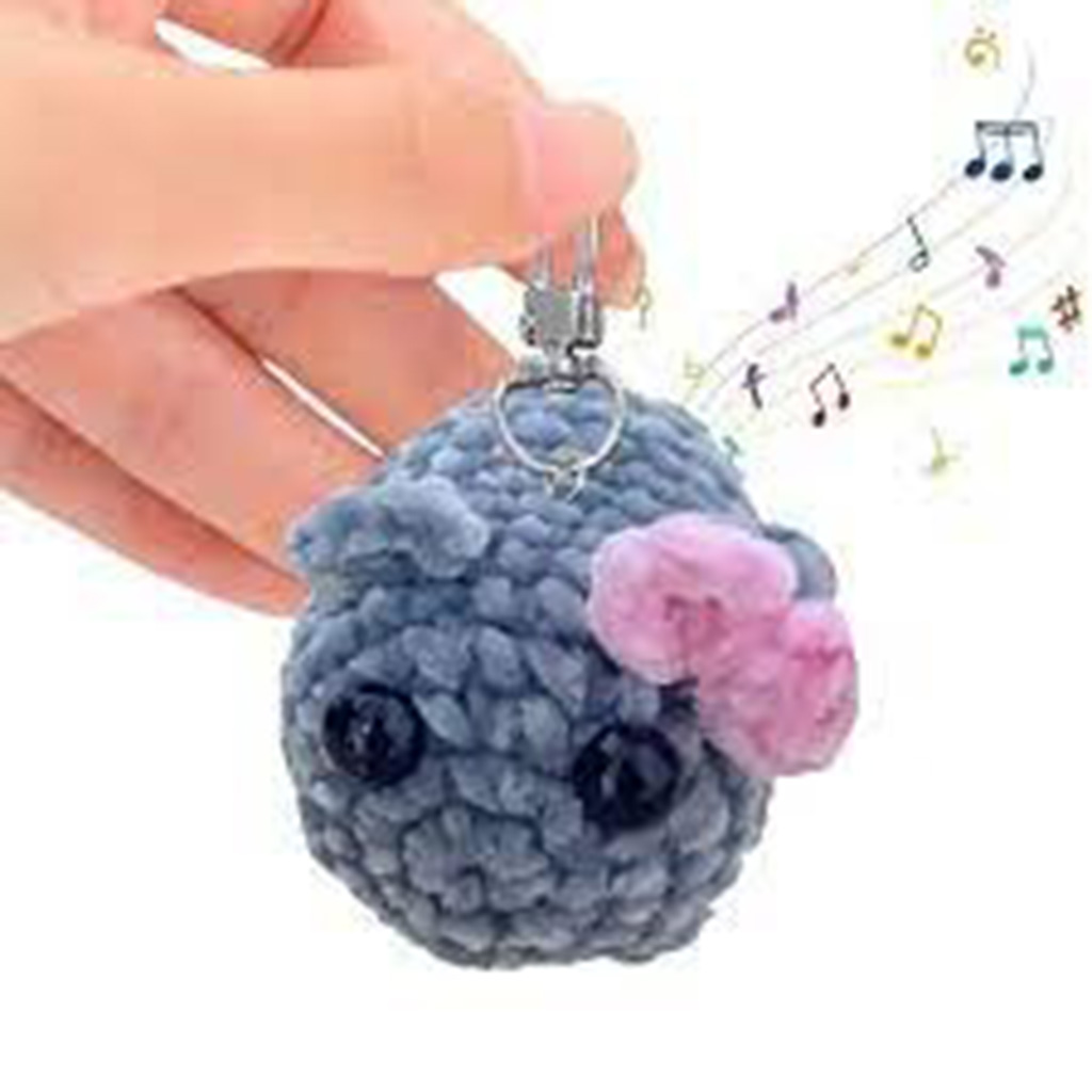 Hand holding a gray plush keychain with pink bow and musical notes.