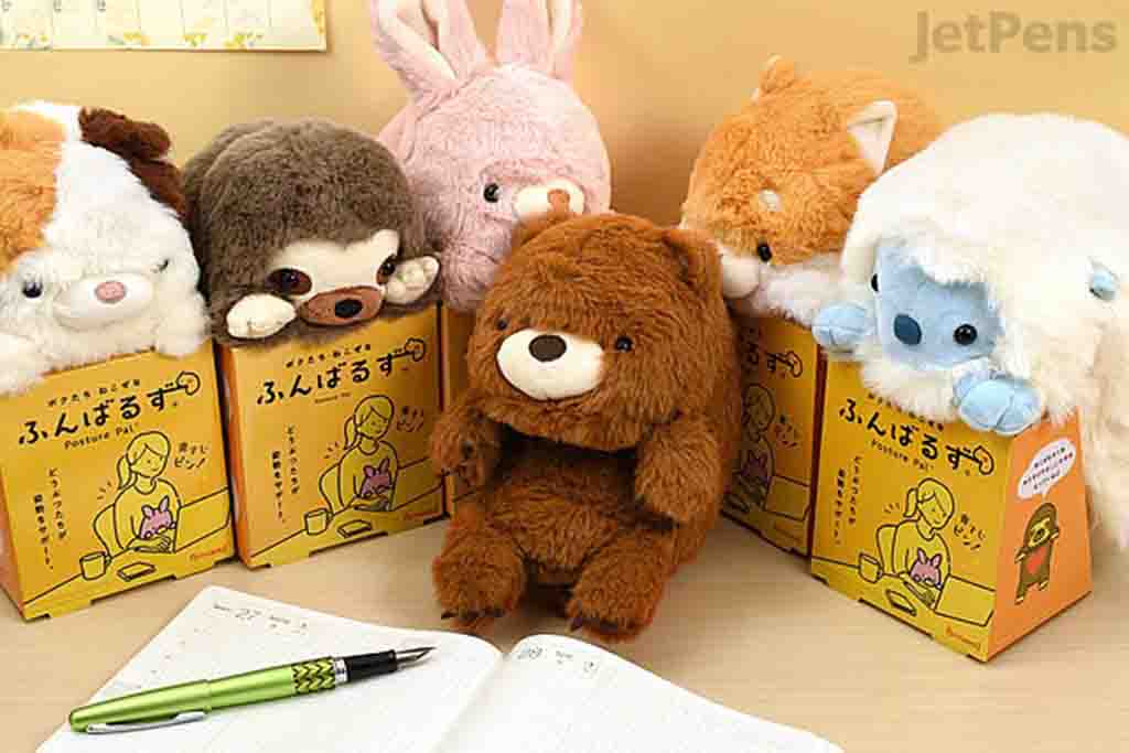 Assorted plush animals displayed on desk with yellow boxes and stationery in background.