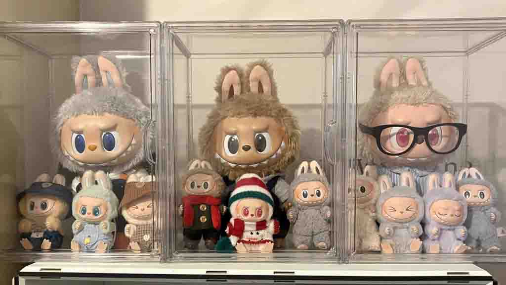Display case filled with large and small Labubu figures, including versions with glasses and festive outfits.