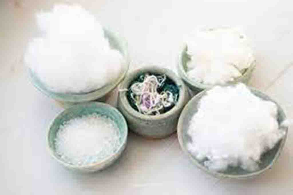 Different types of plush toy stuffing materials displayed in small bowls including fiberfill, foam, and beads.