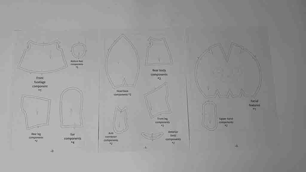 Printed sewing pattern templates showing plush toy components for body, ears, legs, and face.