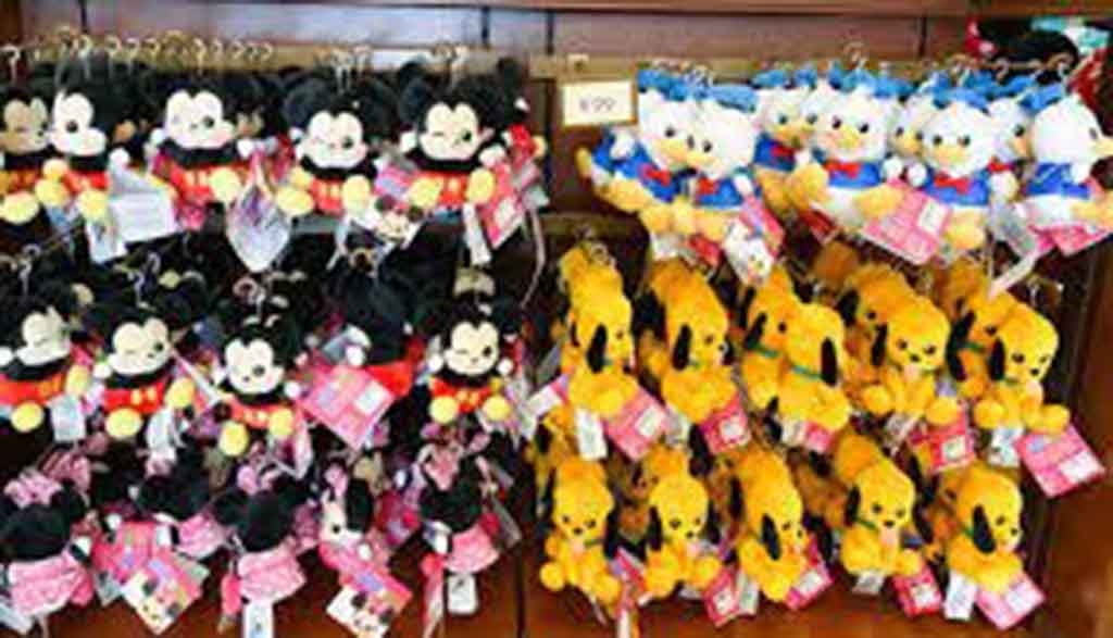 Display of small Disney plush keychains featuring Mickey Mouse, Minnie Mouse, Donald Duck, and Pluto hanging in rows at a store.