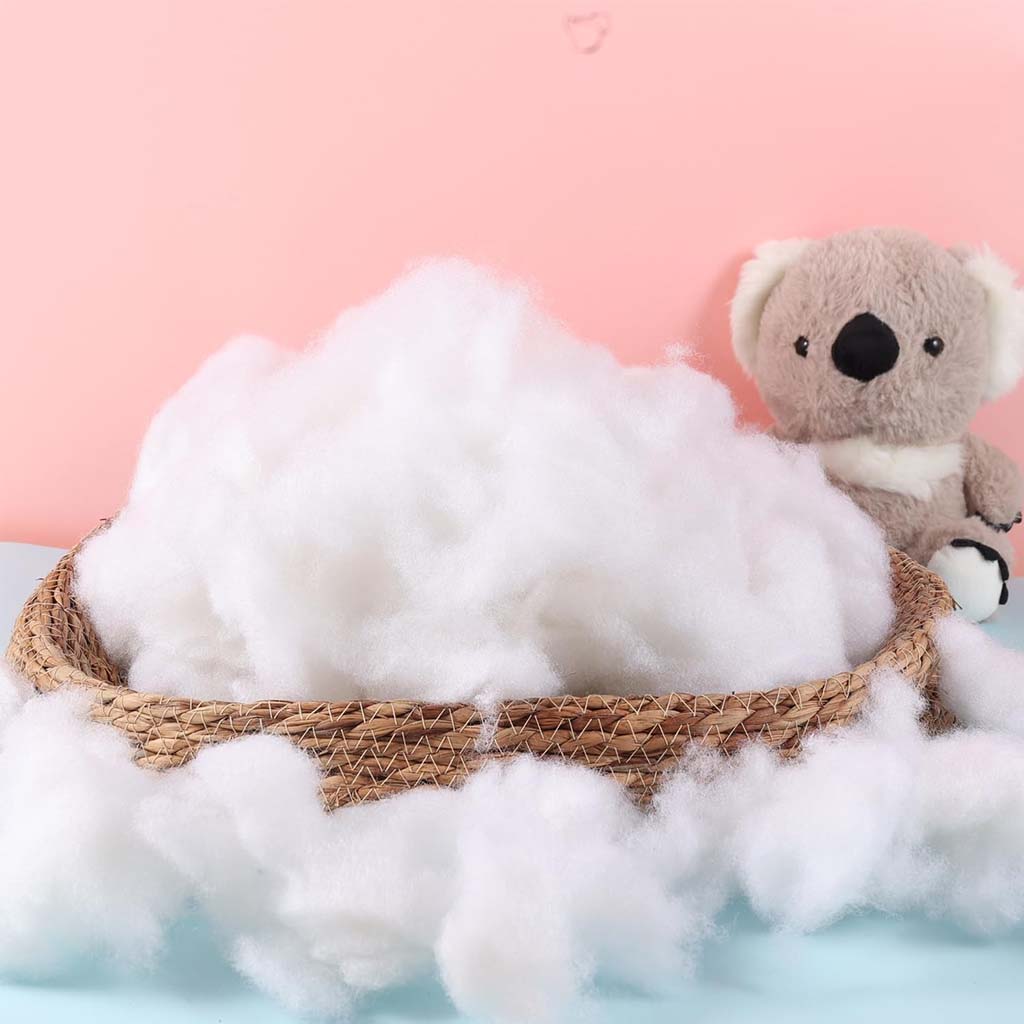 Basket filled with fluffy white polyester fiber stuffing placed beside a stuffed koala toy.