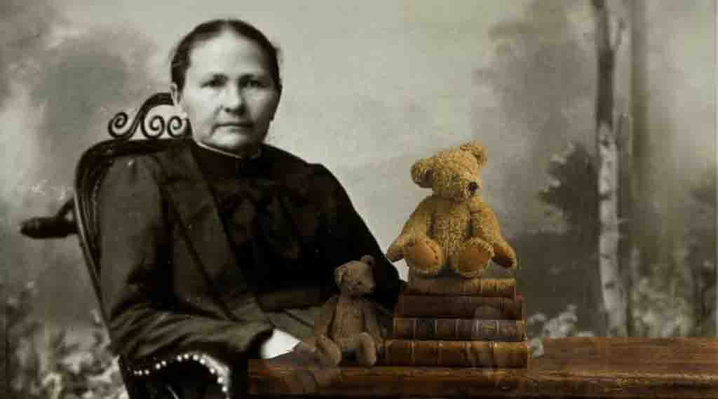 Historical photo of a woman sitting beside a table with old books stacked, topped with two vintage teddy bears.
