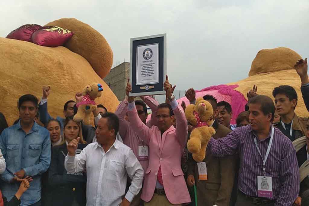 Crowd celebrating with Guinness World Record certificate in front of giant teddy bear.