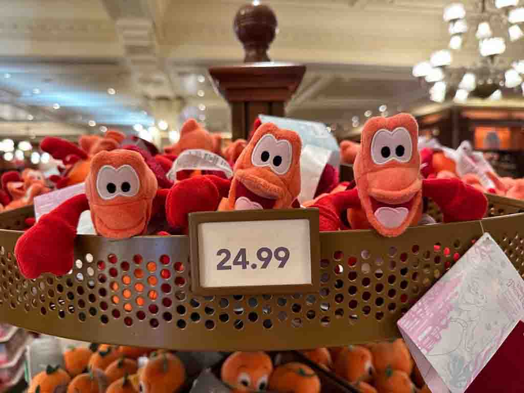 Small Sebastian plush toys from The Little Mermaid displayed in a Disney store with a price tag of $24.99.