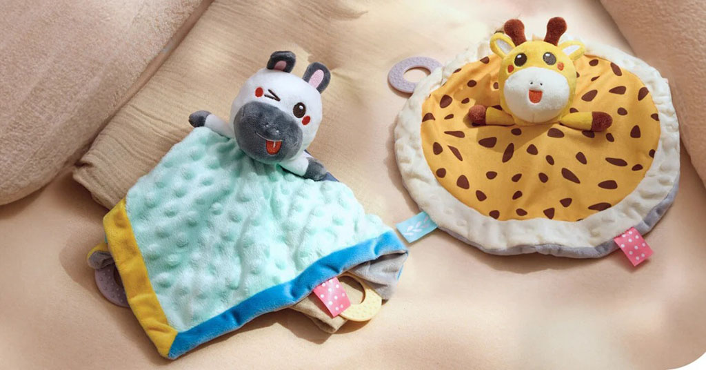Two baby security blankets featuring plush animal heads—one hippo with a blue blanket and one giraffe with a round yellow blanket.