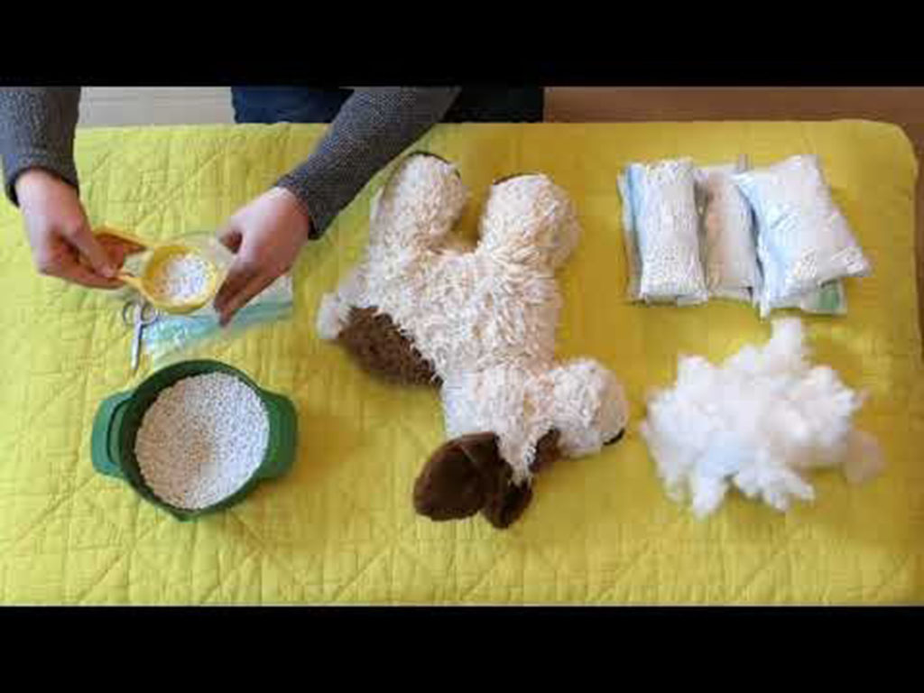 Hands preparing plastic pellets and stuffing materials to insert into a plush dog toy for making a weighted stuffed animal.