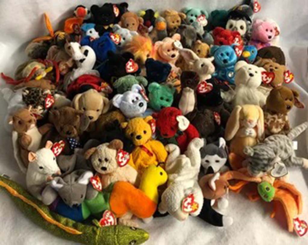 Pile of assorted TY Beanie Baby plush toys in various colors and animal designs, each with the signature red TY heart tag.