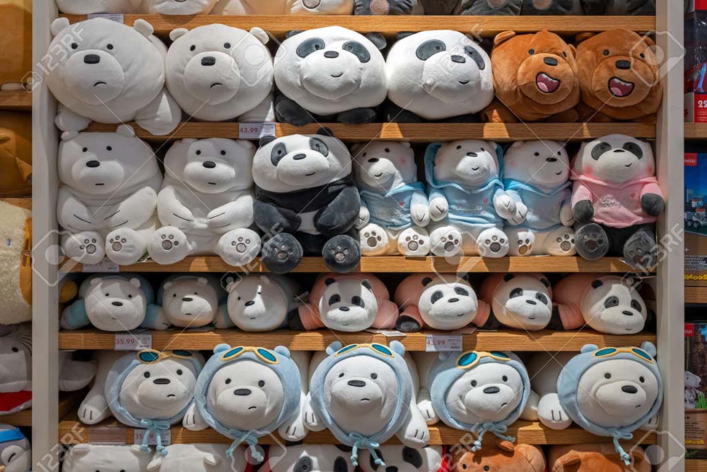 Display of panda, polar bear, and brown bear stuffed toys neatly arranged on wooden store shelves.