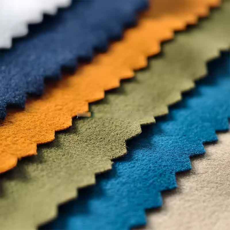 Close-up of colorful brushed plush fabric swatches in blue, orange, green, and beige for toy and clothing production.