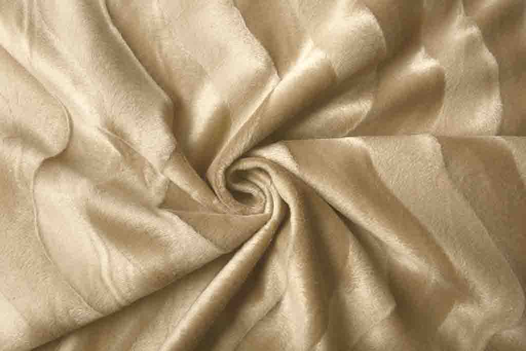Close-up of soft light beige velboa fabric with a smooth short pile texture, arranged in a swirl pattern.