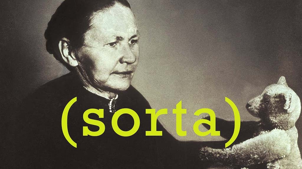 Historical black-and-white photo of an elderly woman holding one of the earliest teddy bears, with the word “sorta” overlaid in yellow text.