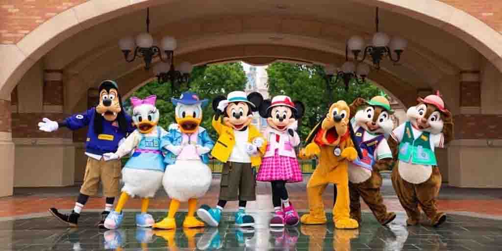 Goofy, Daisy Duck, Donald Duck, Mickey Mouse, Minnie Mouse, Pluto, Chip, and Dale posing together in colorful outfits at Disneyland.
