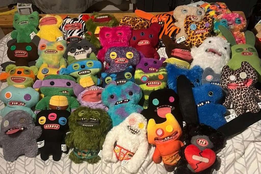 A large assortment of quirky monster plush toys with button eyes, bright colors, and unique patterns displayed on a bed.