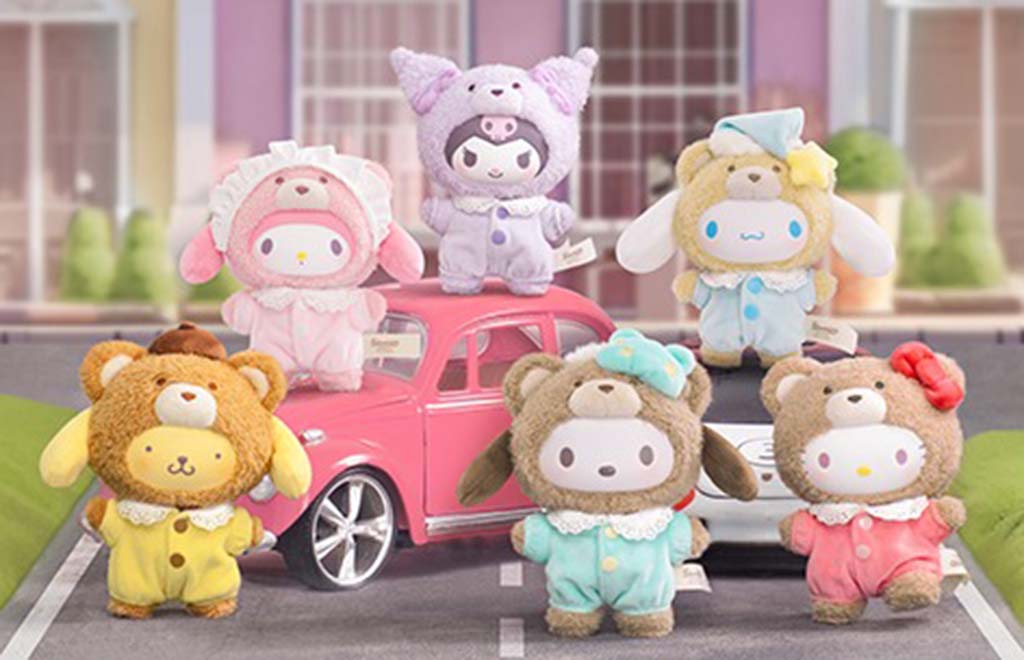 Group of adorable Sanrio plush toys in colorful bear-themed pajamas posed around a pink toy car, featuring pastel designs and playful character expressions.