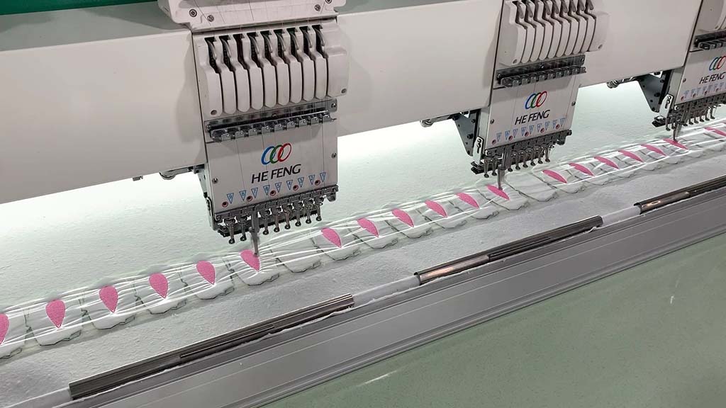 Automated embroidery machines stitching pink fabric details for plush toys using precision computerized patterns.