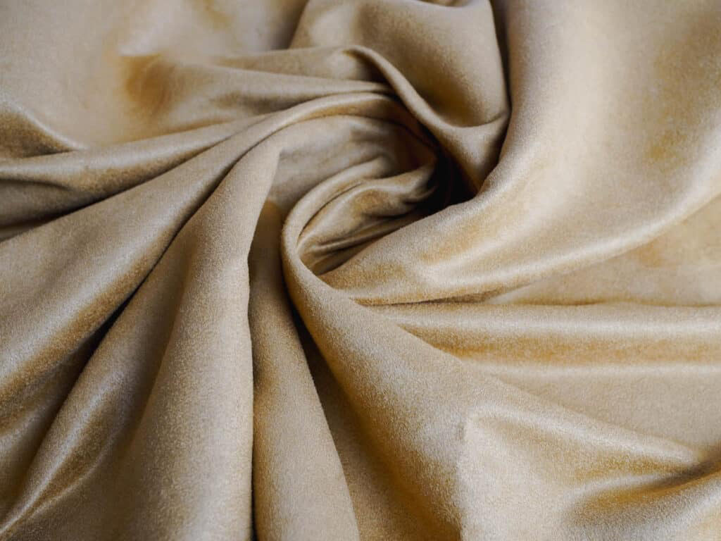 Close-up of soft yellow faux suede fabric with a smooth, velvety texture and gentle folds.