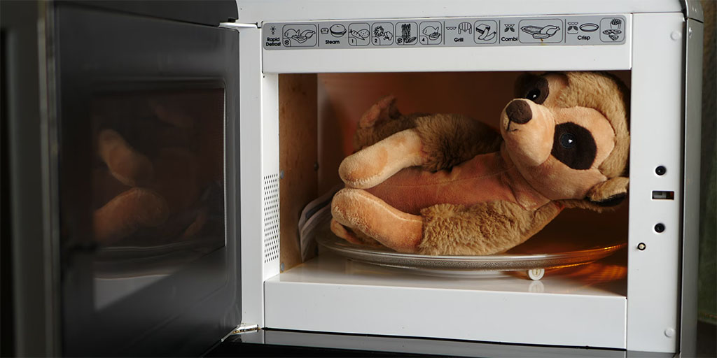 Brown plush meerkat-style stuffed animal placed inside a microwave, illustrating how microwavable plush toys are warmed for comfort use.