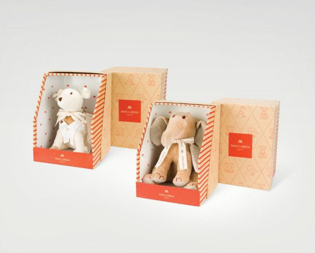 Two plush toys — a bear and an elephant — displayed in elegant Maclaren-branded packaging boxes with soft beige and red patterns, showcasing luxury toy presentation.