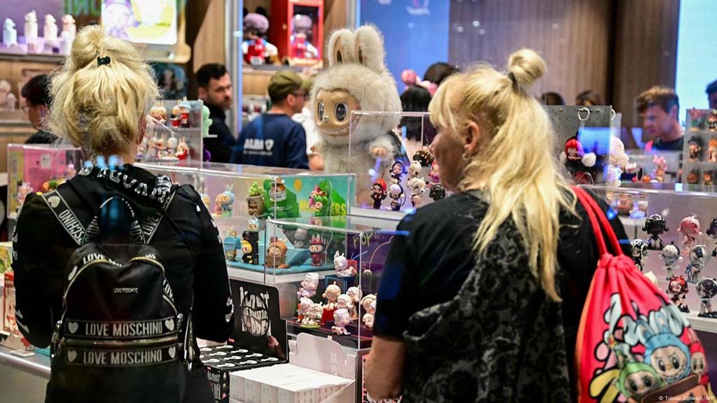 Visitors browsing collectible designer toys displayed in glass cases at a toy exhibition or convention.