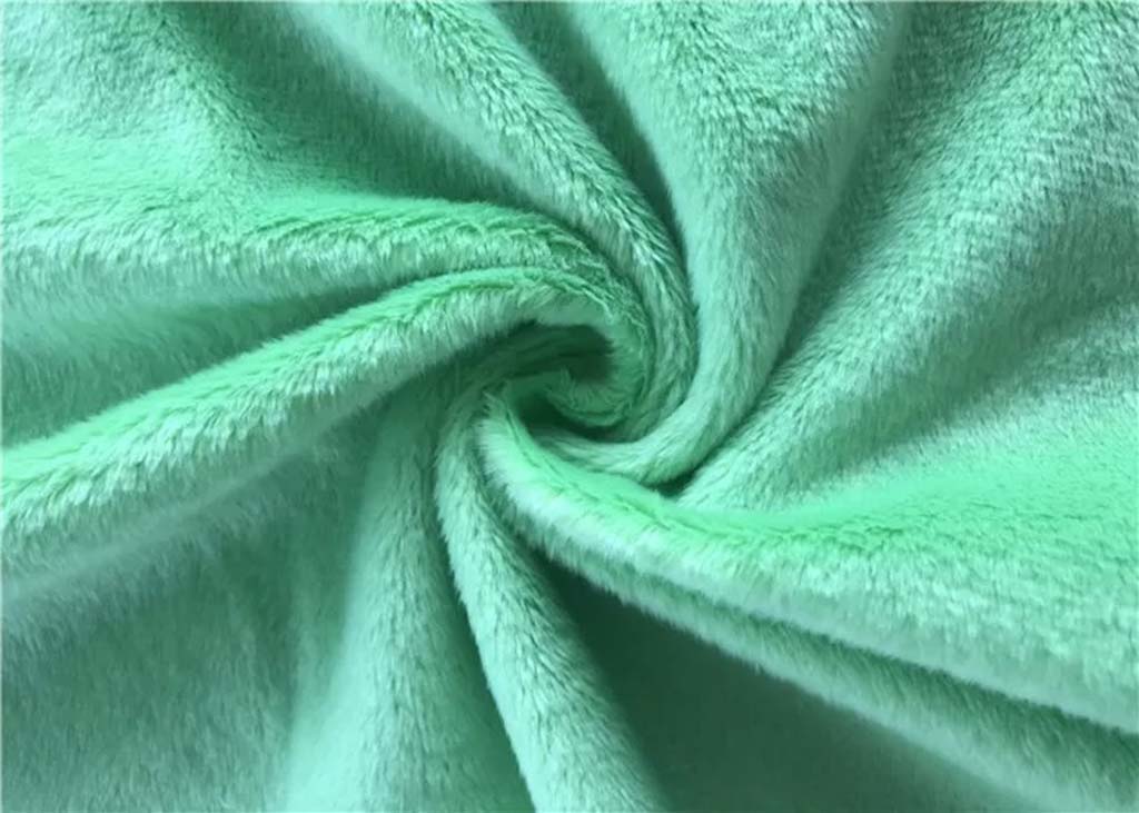 Close-up of mint green minky fabric with soft short fibers, ideal for plush toys and baby products.
