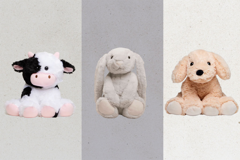 Three plush toys — a black and white cow, a cream bunny, and a light brown puppy — sitting side by side against a neutral background.