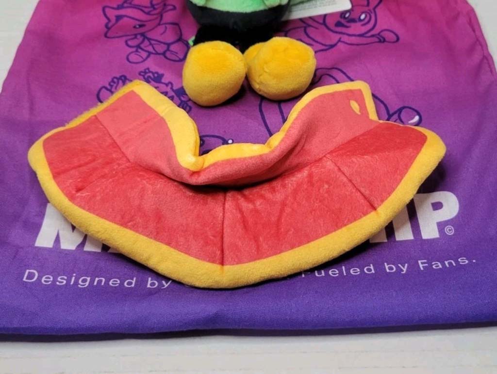 A colorful red and yellow plush accessory piece displayed on a purple cloth bag, likely part of a custom plush toy outfit or costume.