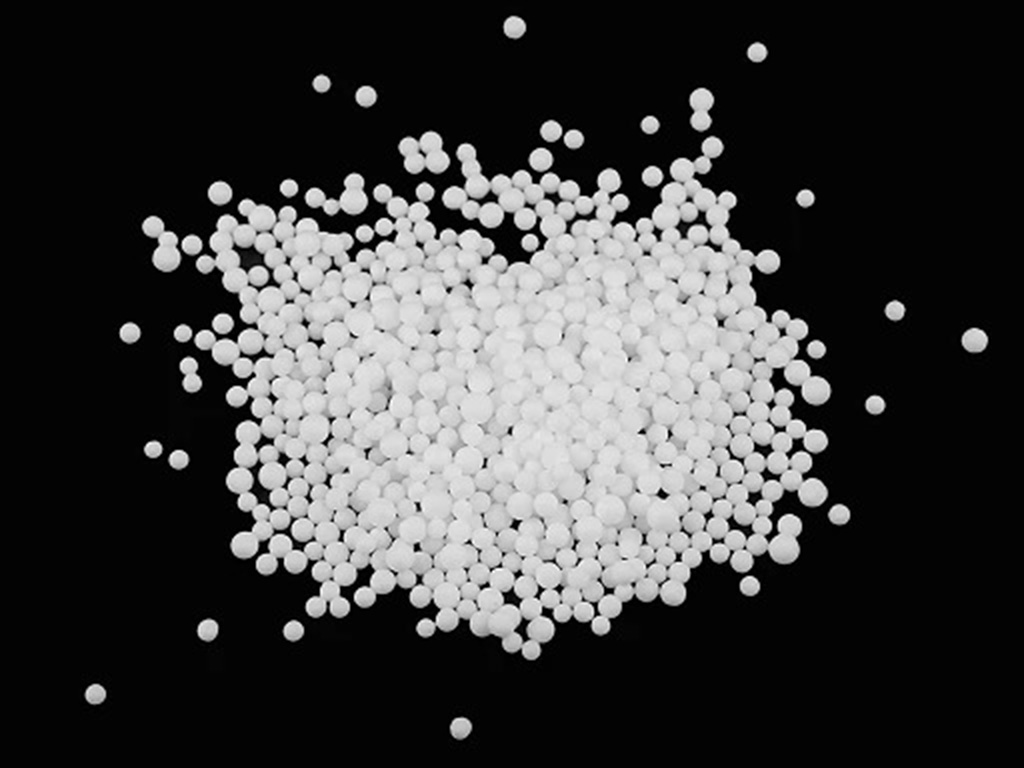 White plastic pellets or microbeads used as stuffing material for weighted plush toys and bean bags on a black background.