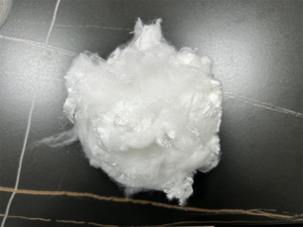 A close-up of a fluffy white ball of virgin polyester staple fiber used as filling material for plush toys and pillows.