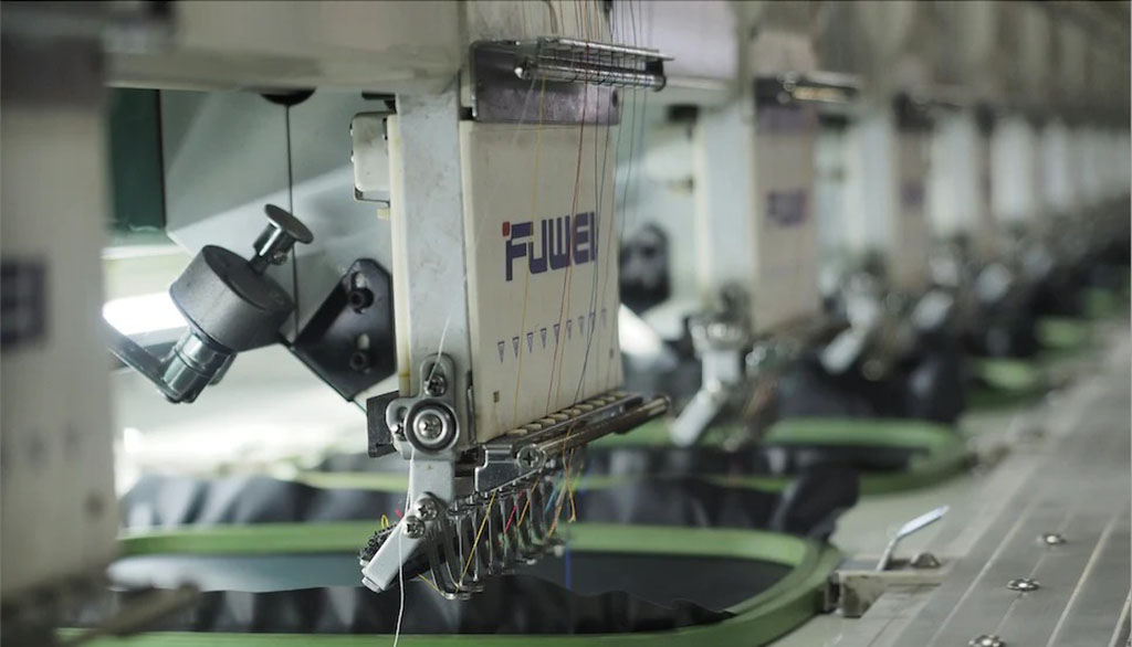 Close-up of automated embroidery machines stitching fabric in a plush toy manufacturing line.