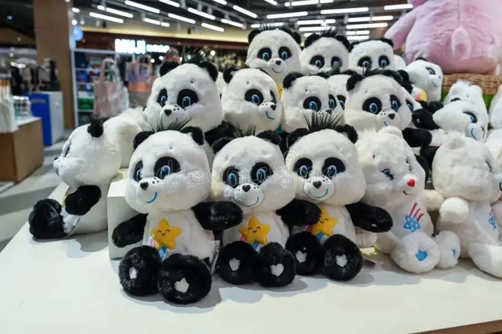 Group of cute panda plush toys with embroidered stars, neatly arranged on a store display table under bright retail lighting.