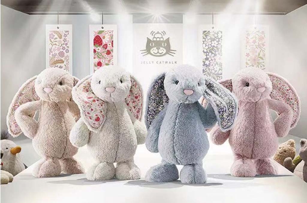 Four Jellycat bunny plush toys with floral-patterned ears displayed in a soft-lit showroom setting.