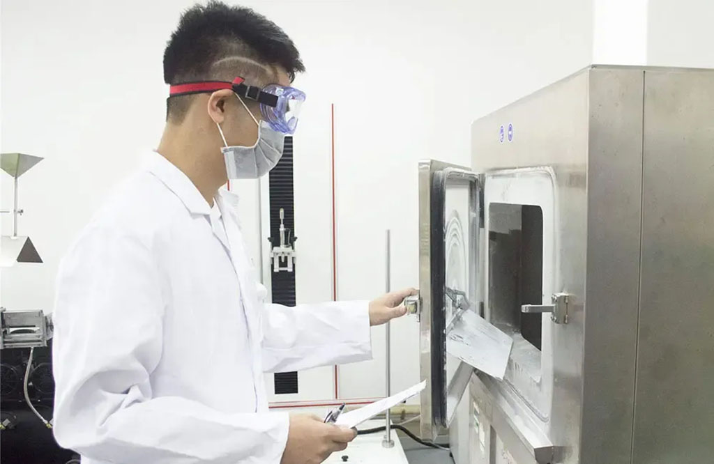 A lab technician wearing safety goggles and a mask conducts a quality test using industrial equipment in a toy safety laboratory.