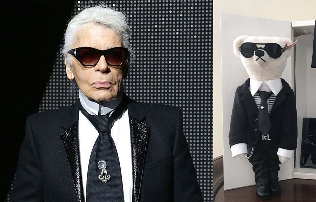 A plush teddy bear dressed in a stylish black suit, white shirt, tie, and sunglasses, displayed beside a man wearing a matching outfit.