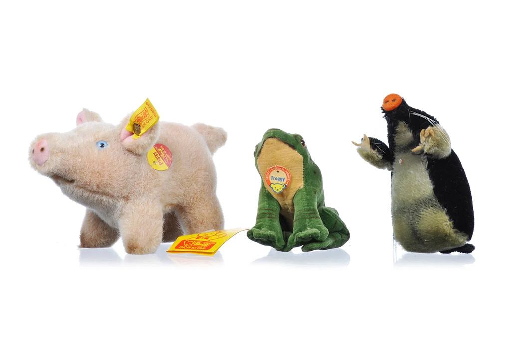 Three vintage plush toys including a pig, a frog, and a mole with yellow tags displayed on a white background.