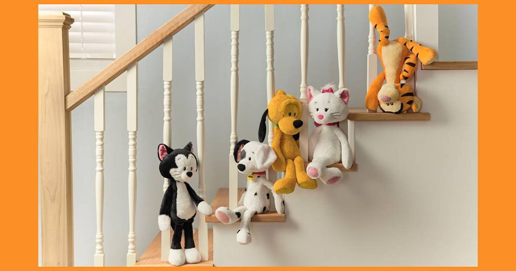 Collection of Disney character plush toys including a cat, dog, and tiger sitting and hanging on wooden stairs.