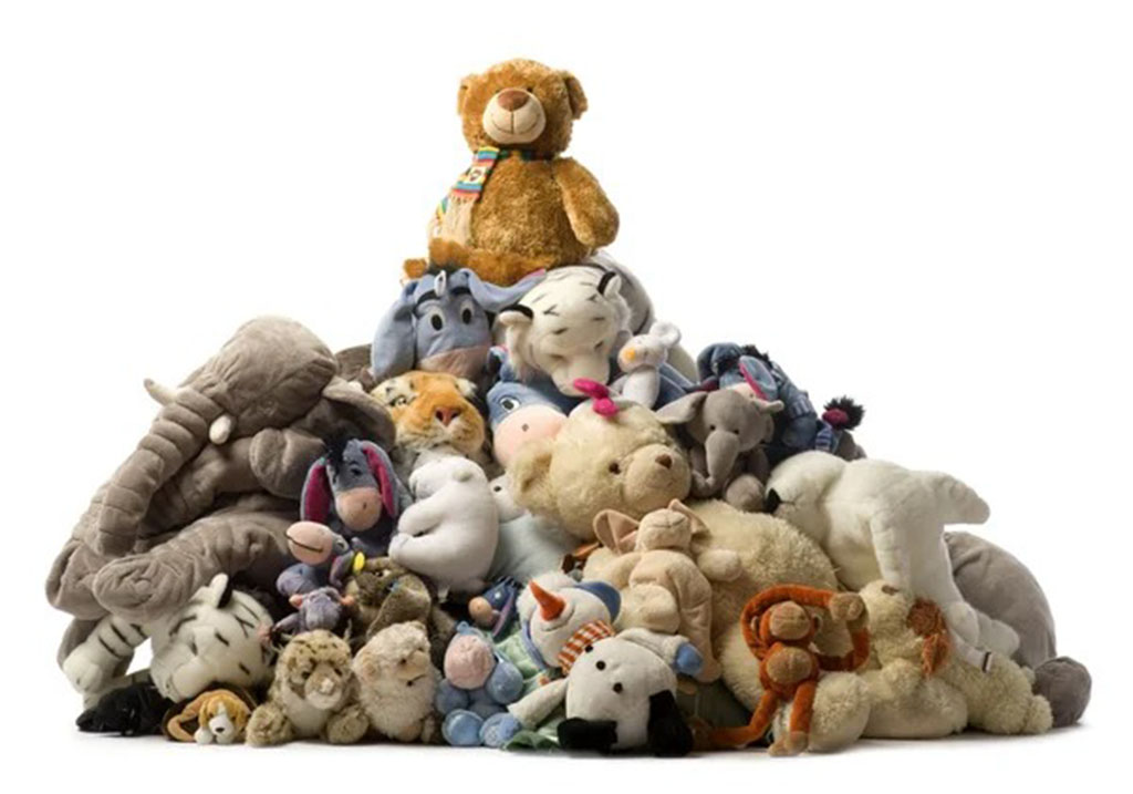 Large pile of assorted plush toys including bears, elephants, and tigers stacked together with a teddy bear on top.