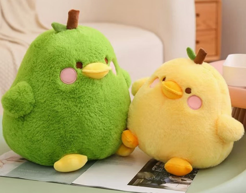 Green and yellow round bird plush toys with pink cheeks and leaf stems sitting on a magazine.