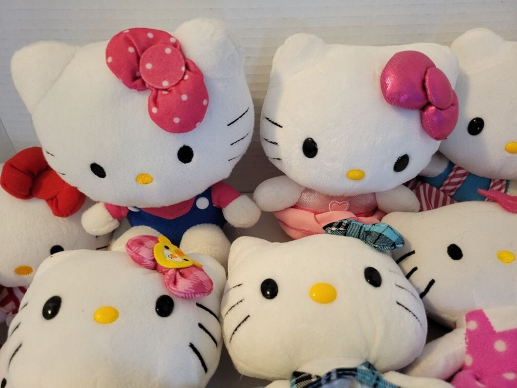 Group of Hello Kitty plush toys wearing colorful outfits and bows in pink, red, and blue.