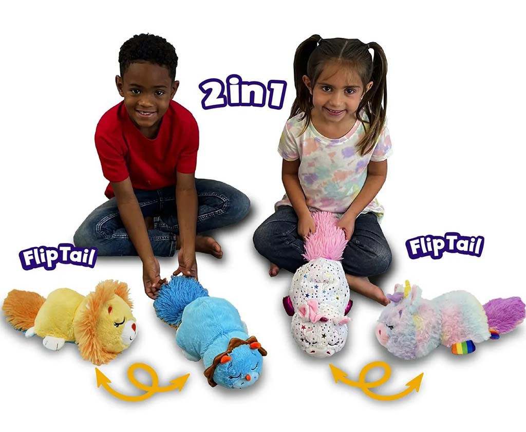 Two children sitting on the floor smiling while playing with colorful 2-in-1 FlipTail plush animals that transform by flipping their tails.