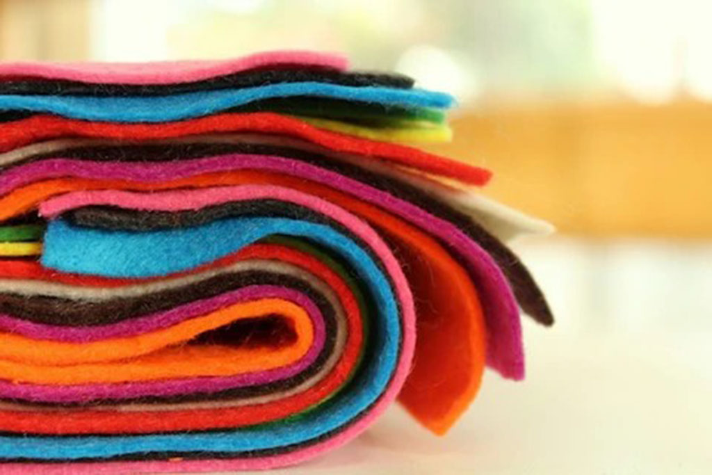 Close-up of rolled felt fabric in bright colors like pink, orange, blue, and black, commonly used for crafting and plush toy detailing.