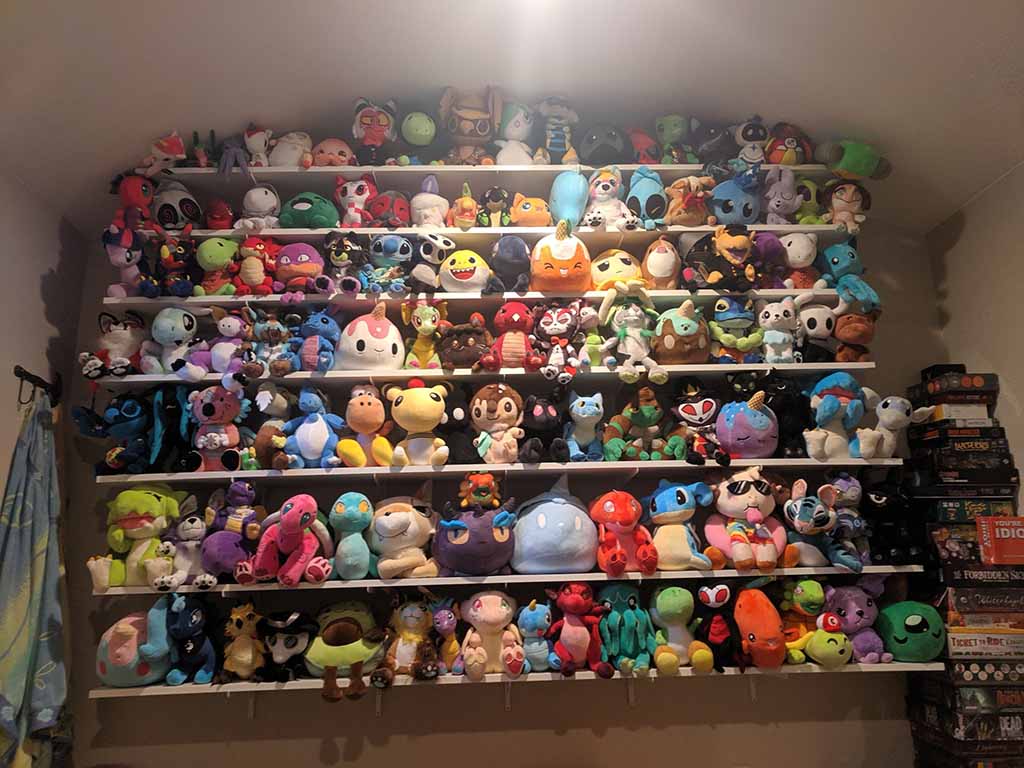 Shelves filled with colorful plush toys of various characters and animals, neatly arranged in a collector’s display under soft indoor lighting.