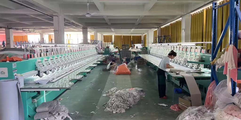 Workers operating long rows of industrial embroidery machines in a plush toy factory, preparing detailed fabric pieces for mass production.