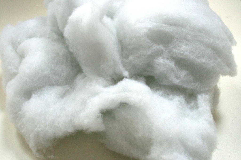 Close-up of soft white polyester fiberfill material commonly used as stuffing for plush toys and cushions.