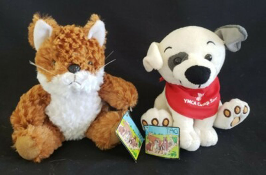  Two plush toys, a brown fox and a white dog with a red scarf, displayed against a dark background.