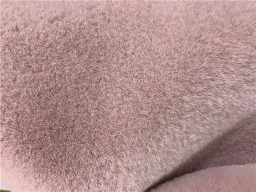 Close-up of pink imitation mink plush fabric showing dense, velvety fibers ideal for making soft toys and stuffed animals.