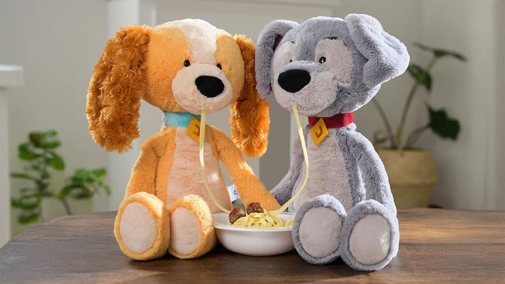 Two plush dog toys sharing a strand of spaghetti over a bowl, inspired by a romantic dinner scene.